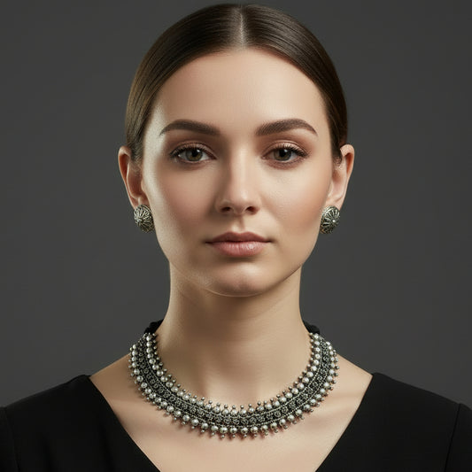 Silver necklace and earrings on a dark background