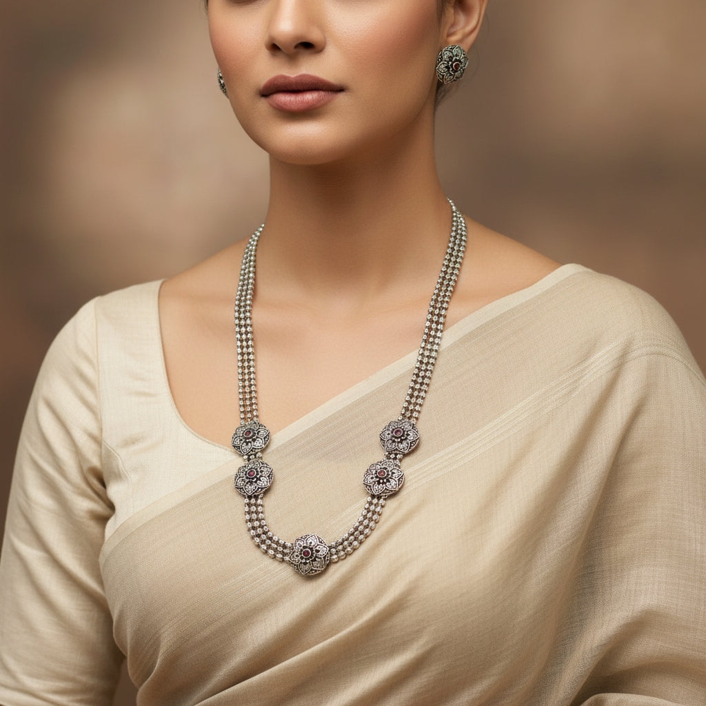 Silver necklace with floral designs and embedded stones on a dark surface