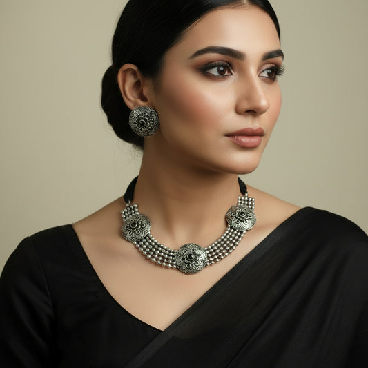 Silver necklace and earrings set on a dark background