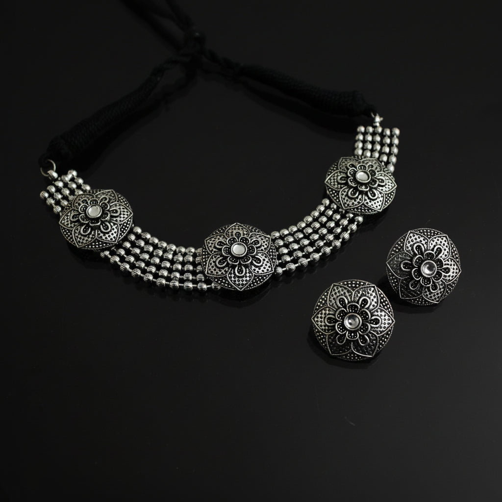 Silver necklace and earrings set on a dark background