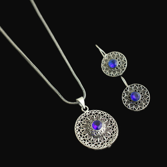 Silver necklace and earrings with blue gemstones on a gray background