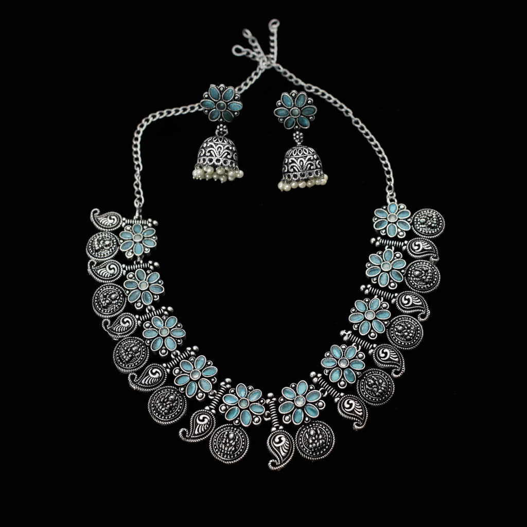 Silver necklace with floral designs and matching earrings on a gray background