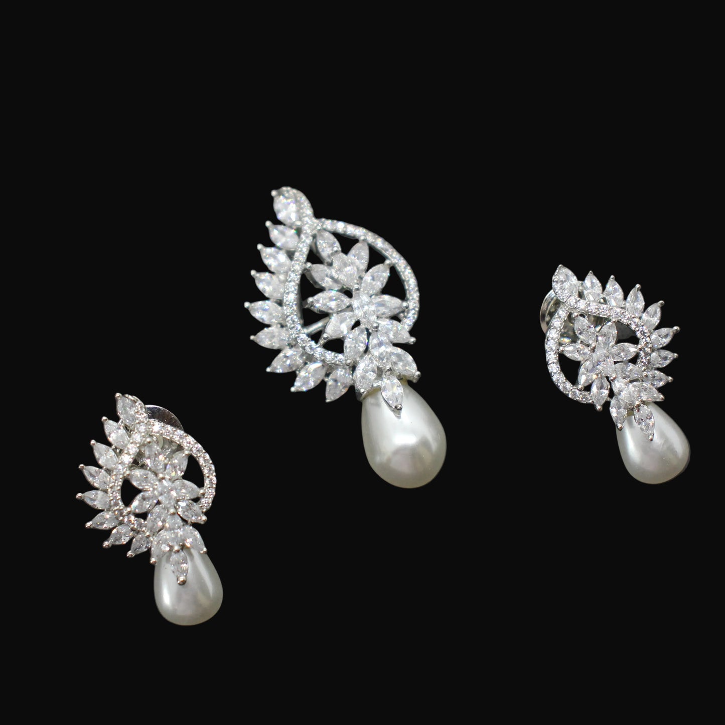 Jewelry set with silver earrings and a necklace on a dark background
