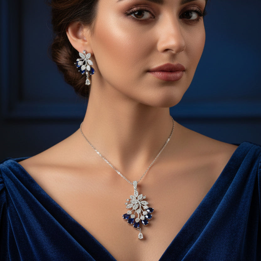 Pair of silver floral earrings with blue gemstones on a dark background
