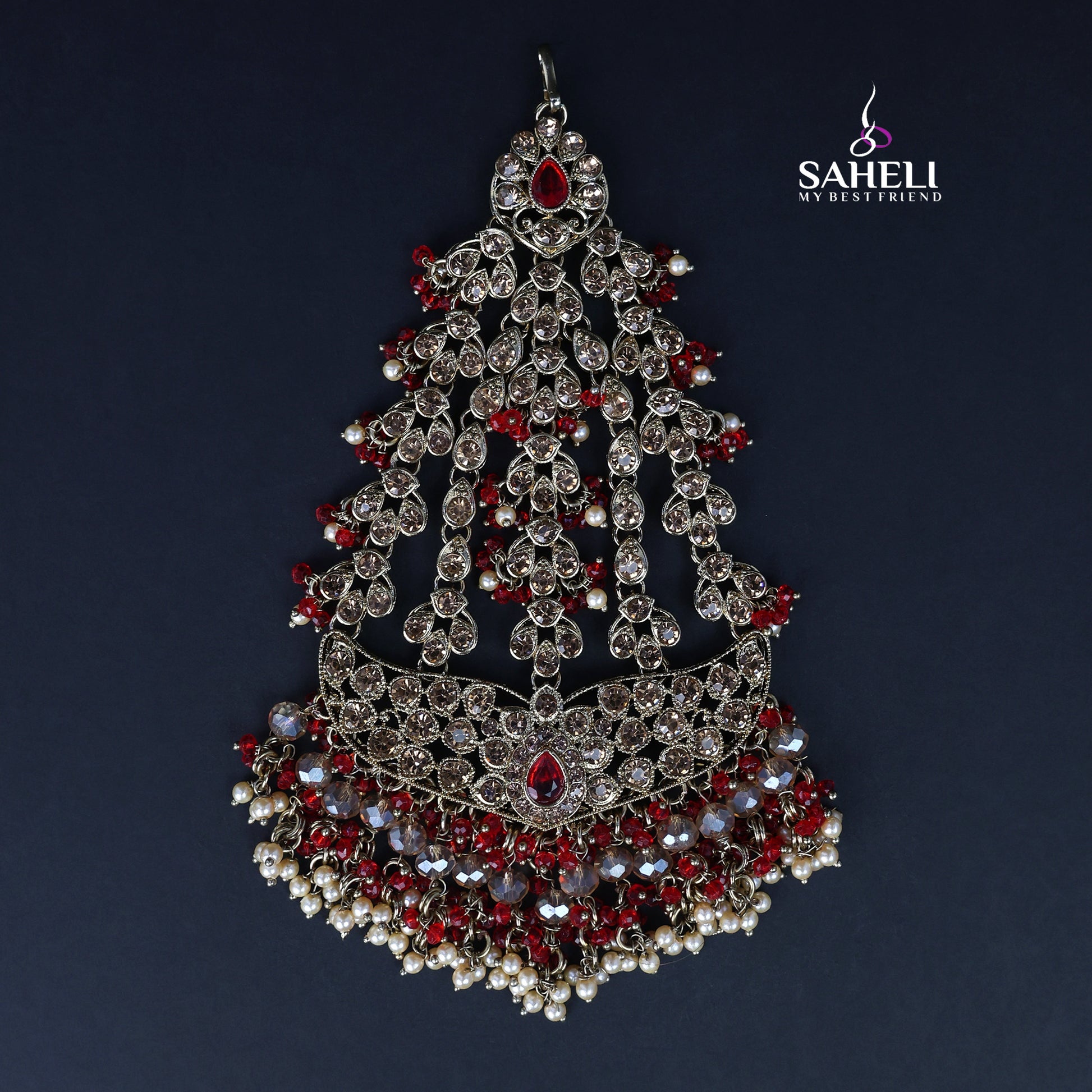 Ornate silver and red jewelry piece with 'SAHELI' branding on a dark background