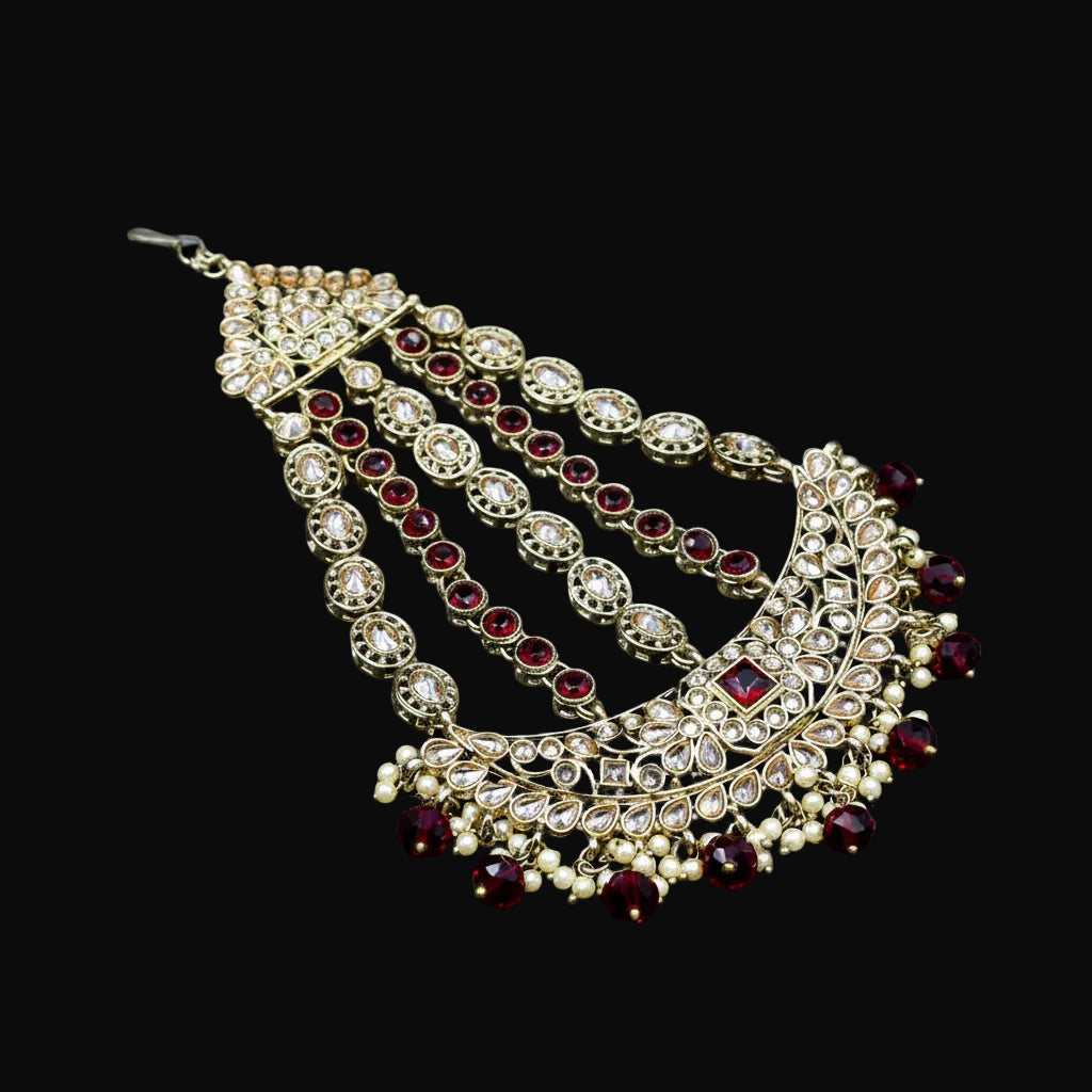 Ornate necklace with red stones on a dark background, featuring the brand 'Saheli'.