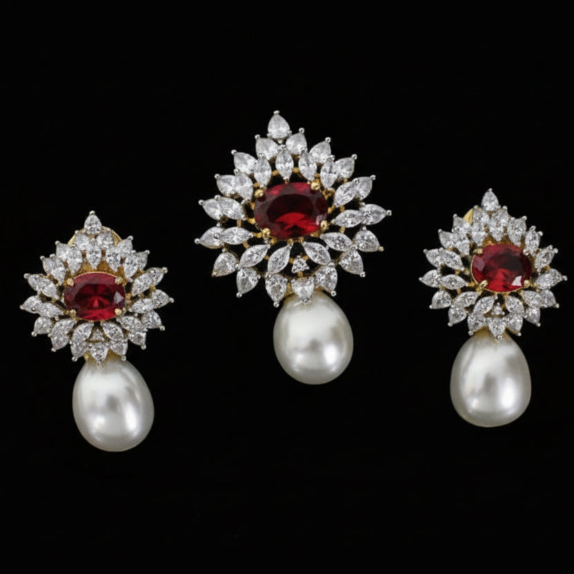 Pair of earrings with red gemstones and pearl drops on a black stand.