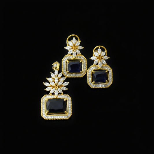 Gold and black earrings with 'Saheli' branding on a dark background