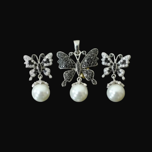Butterfly-shaped earrings with pearl drops on a dark background, featuring the brand 'Saheli'.