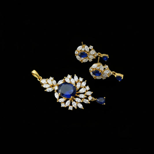 Gold earrings with red gemstones on a gray background, branded 'Saheli'.