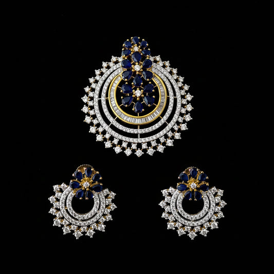 Ornate earrings with blue and gold accents on a dark background, featuring the brand 'Saheli'.