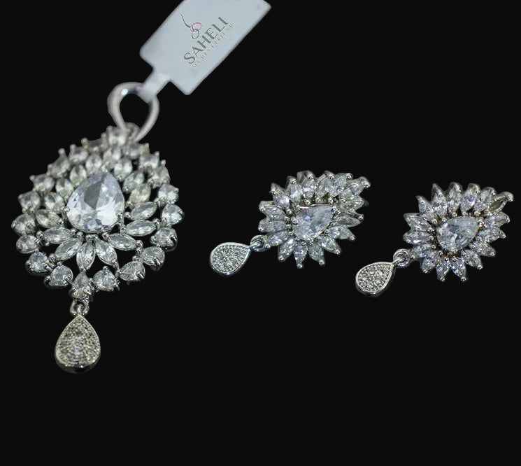 Silver jewelry set with pendant and earrings on a dark background