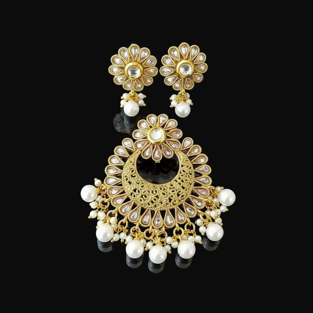 Gold and pearl earrings on a black stand with 'SAHELLI' branding.