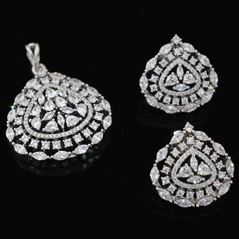 Diamond teardrop pendant and earrings on a dark background