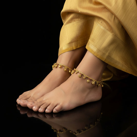 Gold necklace with red stones on a black background, featuring the brand 'Saheli'.
