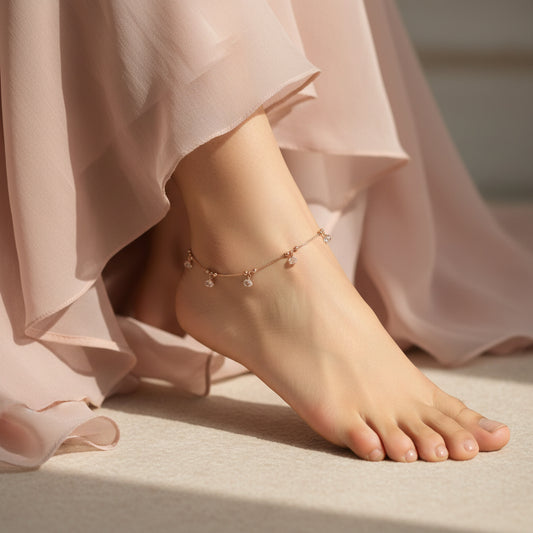 Gold anklet with crystals on a dark background, featuring the brand 'Saheli'.