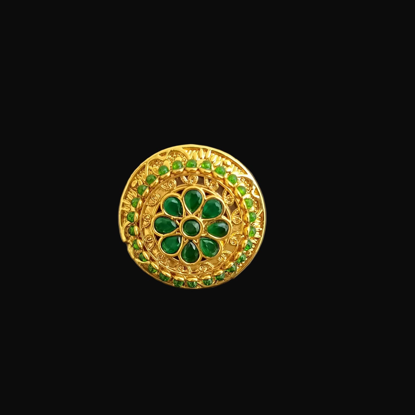 Gold brooch with green gemstones on a gray background