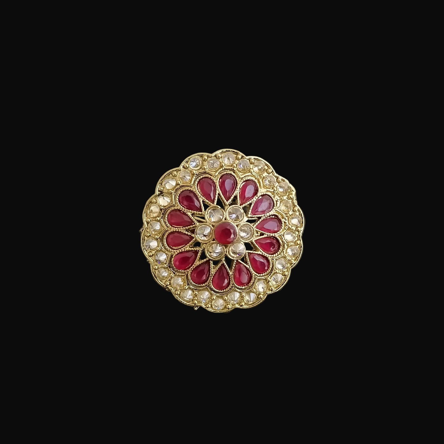 Decorative brooch with red gemstones and gold accents on a dark background