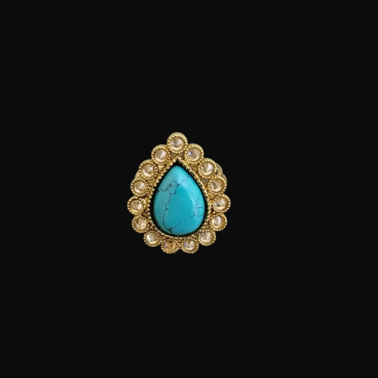 Ring with turquoise stone and gold accents on a dark gray background