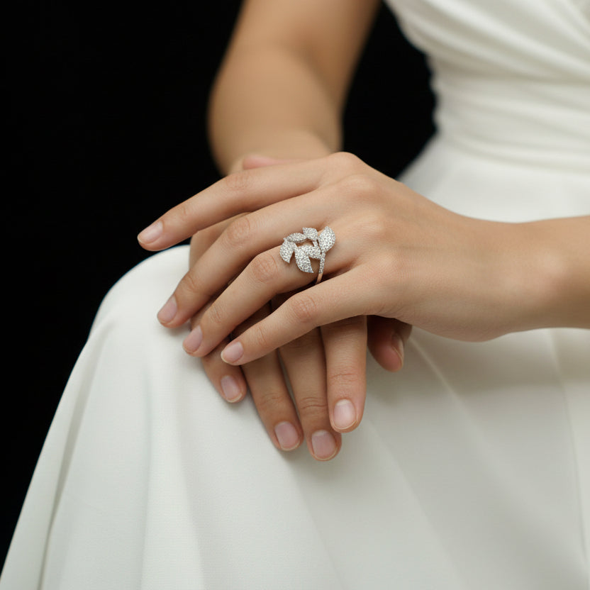 Silver leaf-shaped earring on a dark background with 'Saheli' branding.