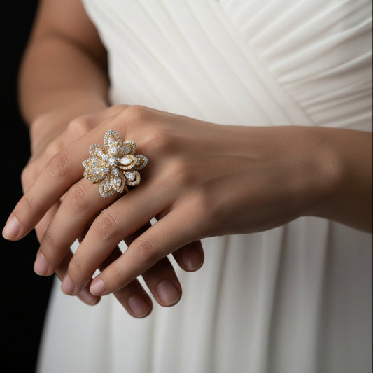 Gold floral ring on a black hand with 'SAHELI' branding.