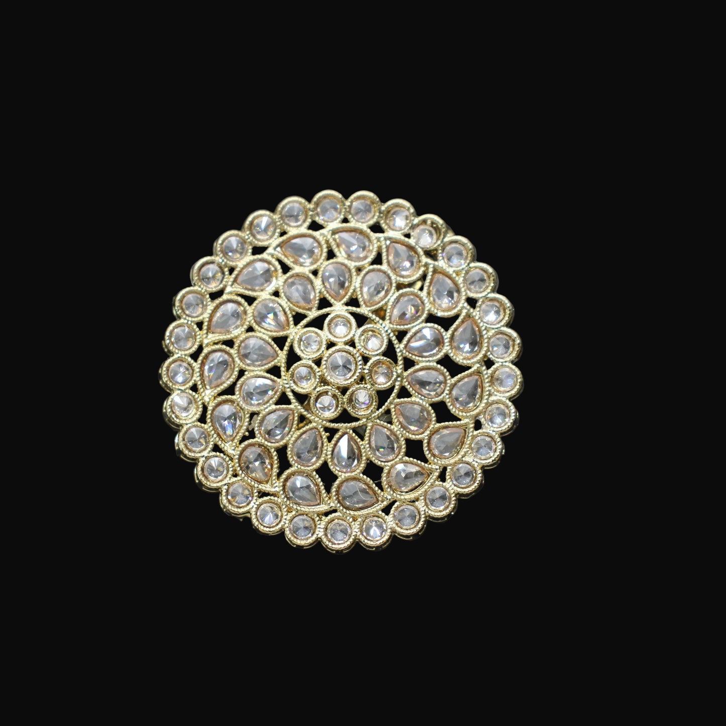Gold ring with circular design and embedded stones on a black mannequin hand.