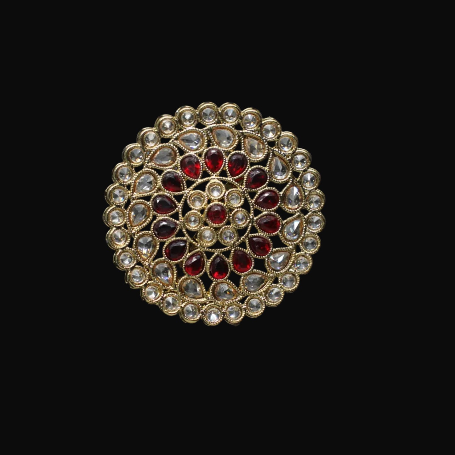 Gold and red gemstone ring on a black hand model against a dark background