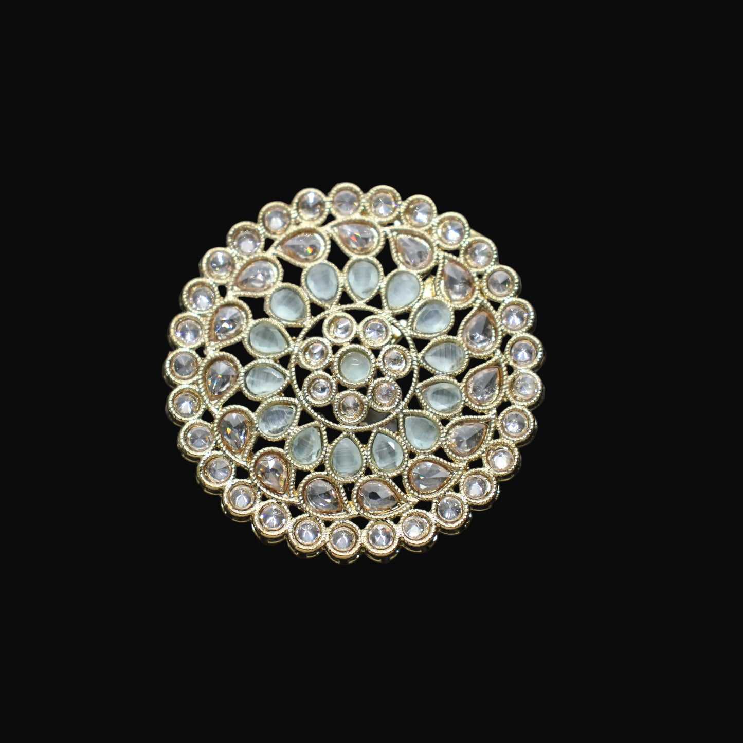 Gold and gemstone brooch on a black mannequin hand against a dark background