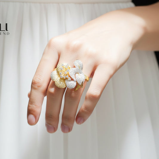 Gold and silver floral ring on a black glove with 'SAHELI' branding.