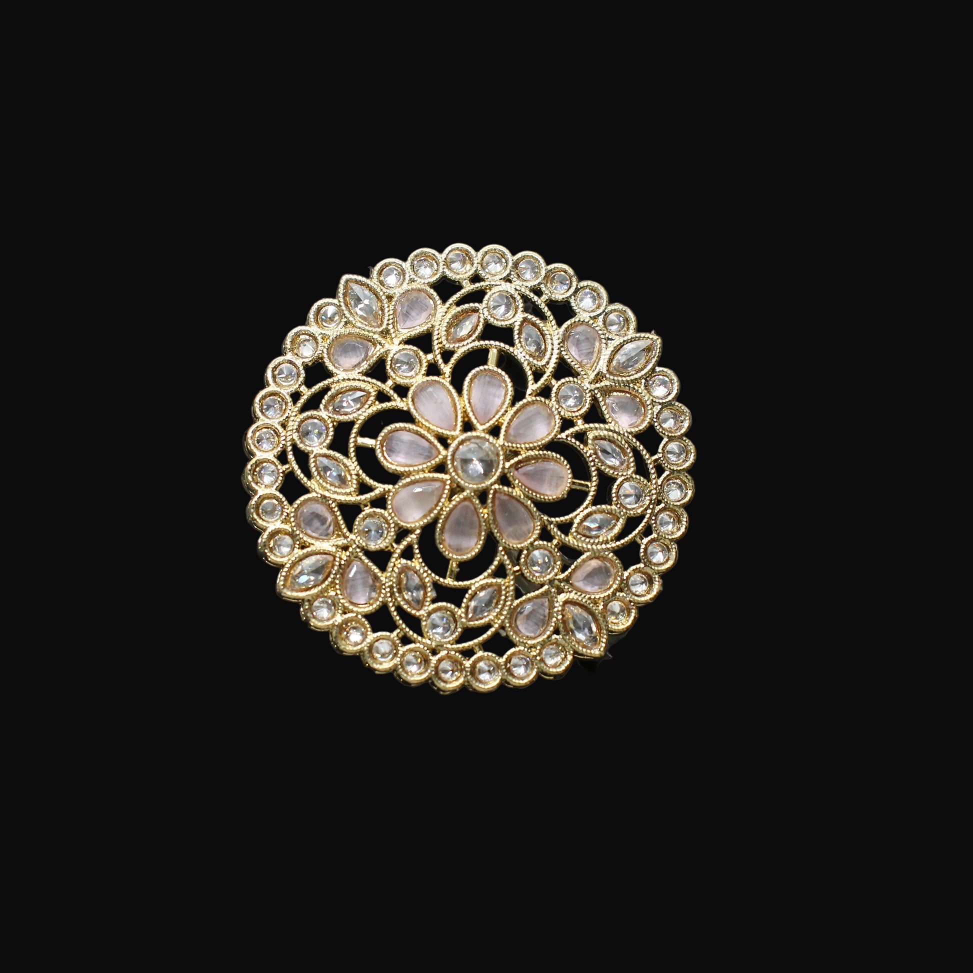 Gold ring with intricate design on a black mannequin hand against a dark background