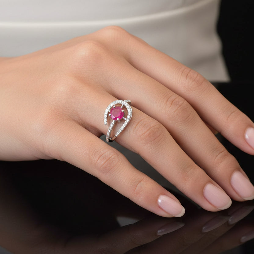 Earring with a red gemstone on a black mannequin hand, branded 'Saheli'.