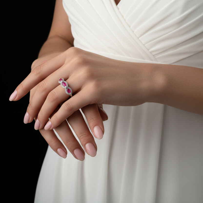 Earring with pink gemstones on a black hand model, brand 'Saheli' visible