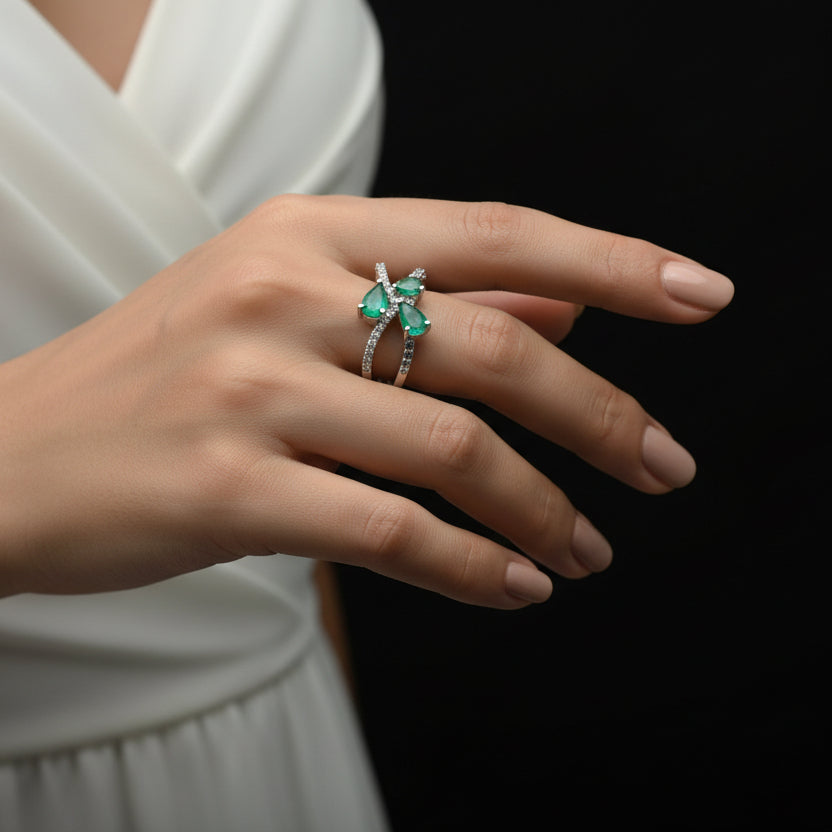 Silver ring with green gemstones on a dark surface, featuring the brand 'SAHELLI'.