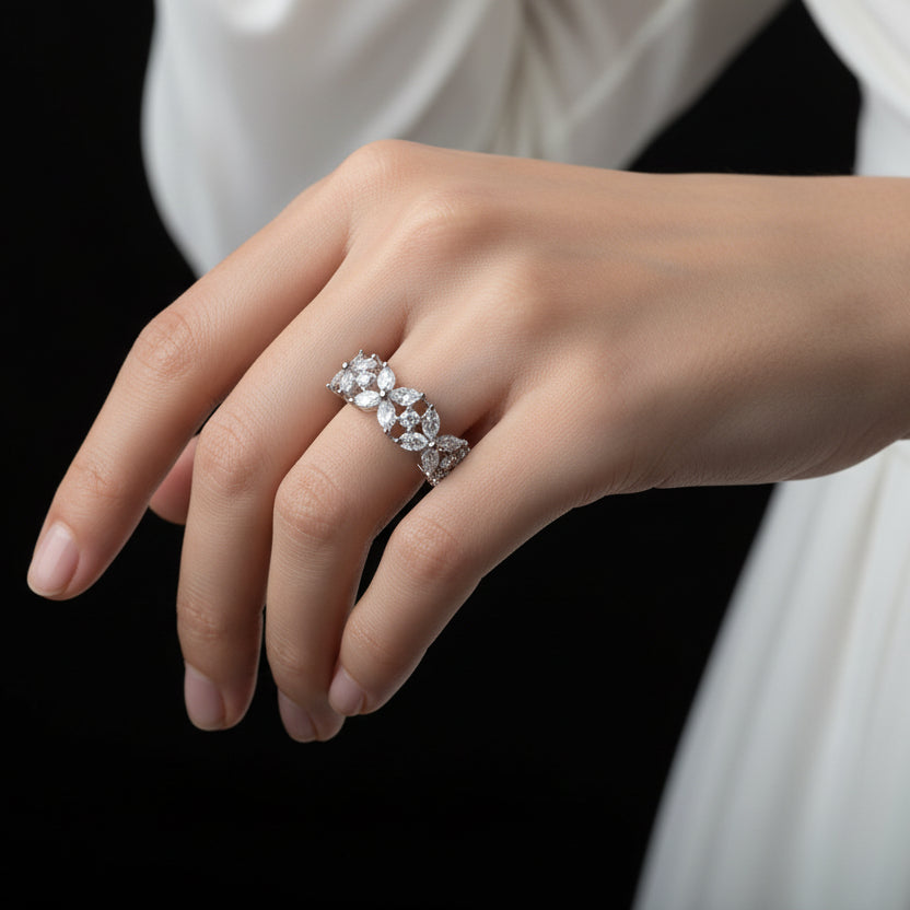 Silver ring with floral design on a black hand, brand 'SAHELI' visible