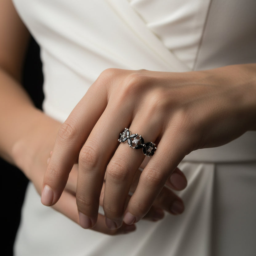 Silver ring with multiple diamonds on a black-gloved hand against a dark background, featuring the brand 'Sahelli'.