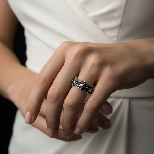 Silver ring with multiple diamonds on a black-gloved hand against a dark background, featuring the brand 'Sahelli'.