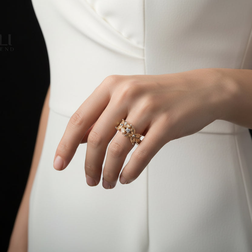 Gold leaf-shaped ring on a black hand with 'SAHELI' branding.