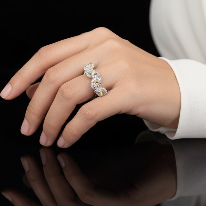 Silver ring with orange gemstones on a gray background, featuring the brand 'Saheli'.