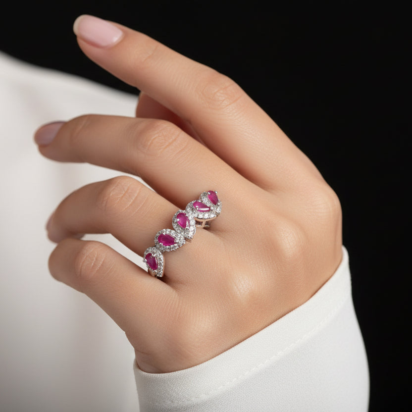 Silver ring with pink gemstones on a gray background, featuring the brand 'SAHELLI'.