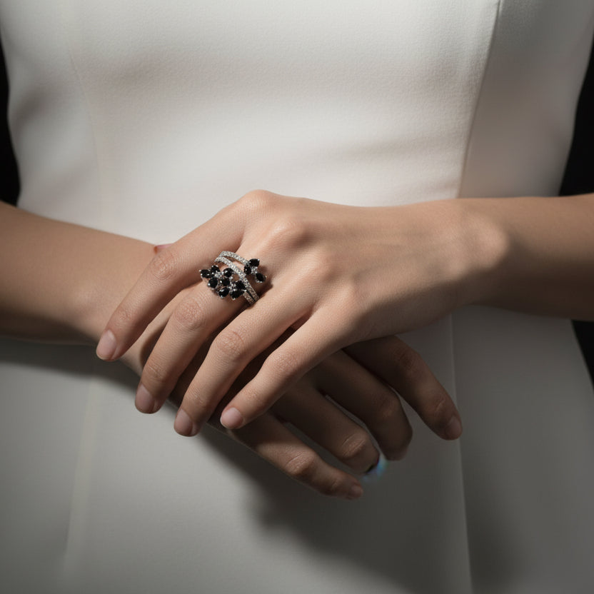 Silver ring with black stones on a gray background, featuring the brand 'Saheili'.