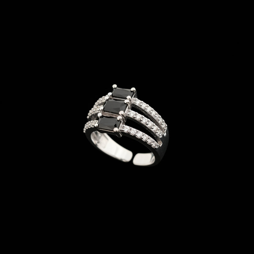Silver ring with a black gemstone on a gray background, featuring the brand 'SAHELI'.