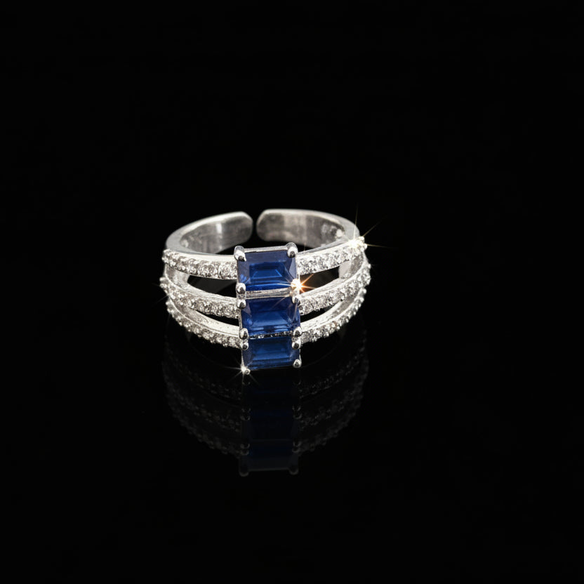 Silver ring with blue gemstone on a gray background with 'SAHELI' branding.