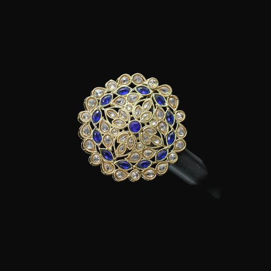 Jewelry ring with blue and gold design on a black mannequin hand against a gray background