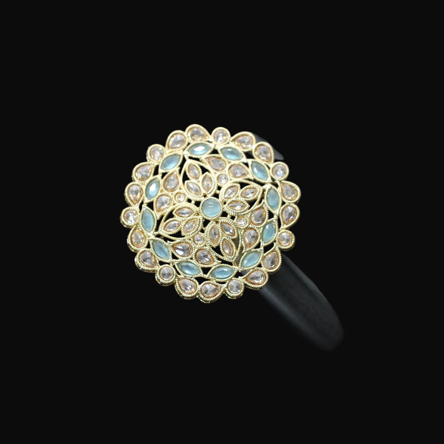 Gold and blue gemstone ring on a black mannequin hand against a gray background