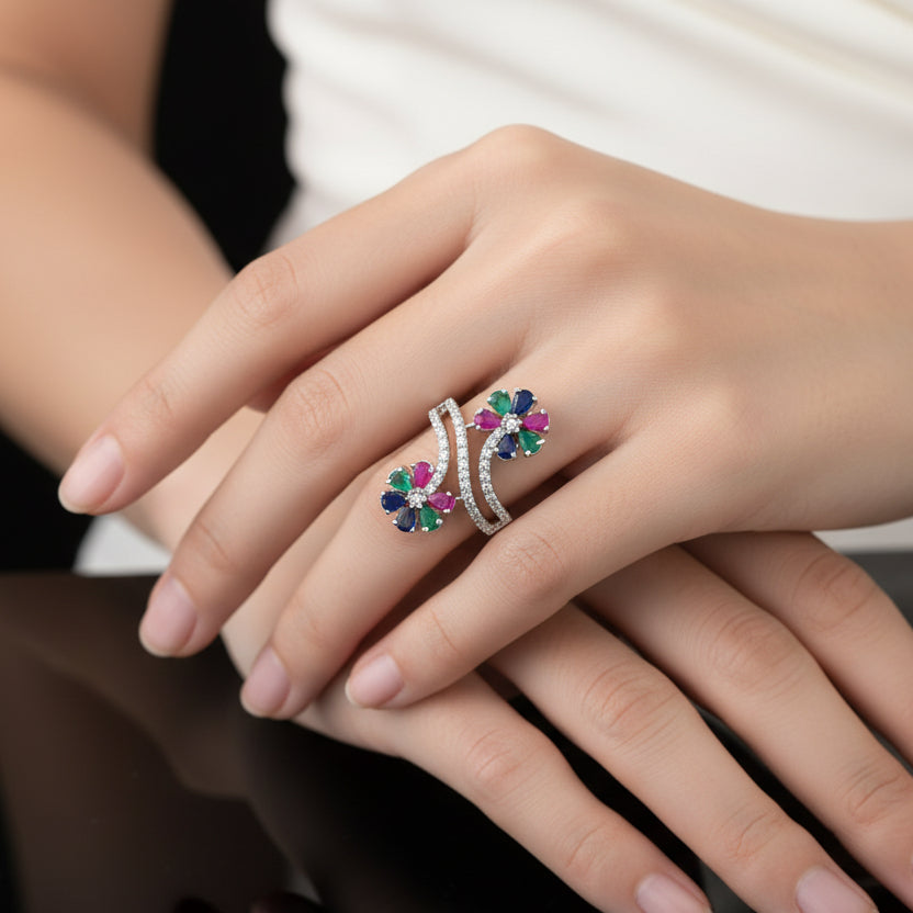 Elegant ring with gemstones on a black mannequin hand, branded 'Saheli'.