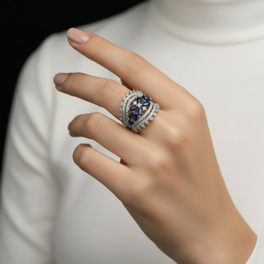 Silver ring with blue gemstones on a gray background, featuring the brand 'Saheli'.