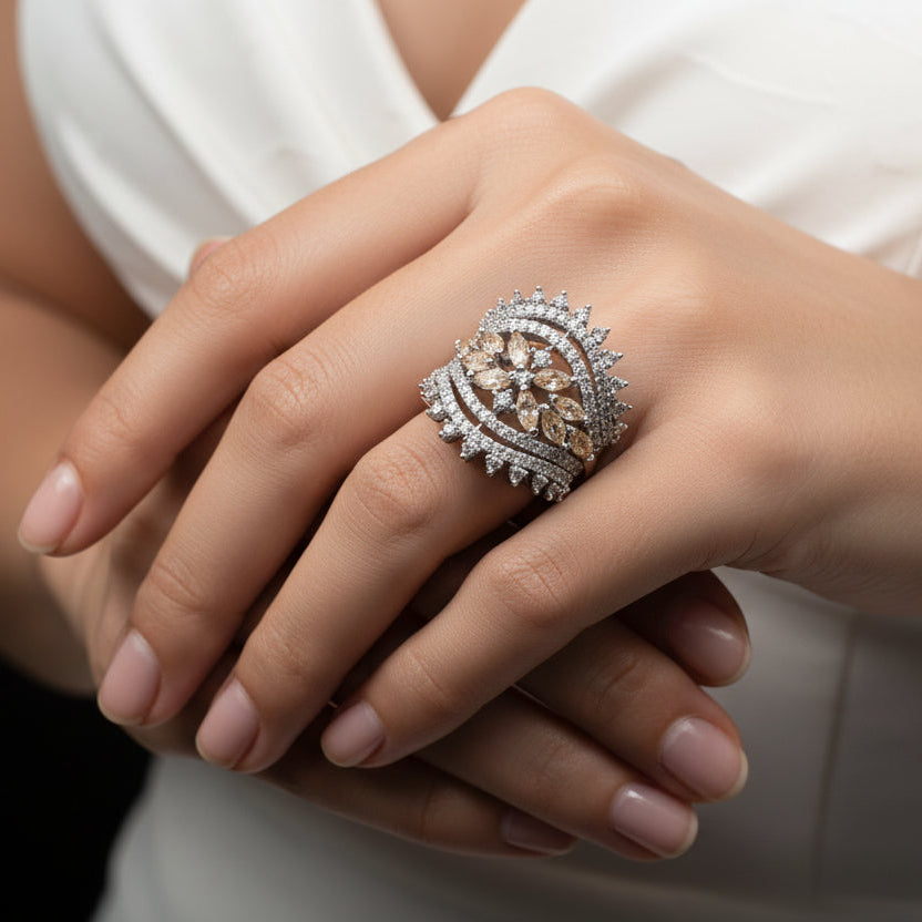 Silver ring with gemstones on a dark gray background, featuring the brand 'Saheli'.