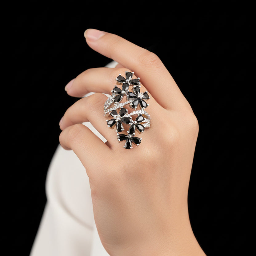 Silver ring with black stones on a gray background, featuring the brand 'Saheli'.