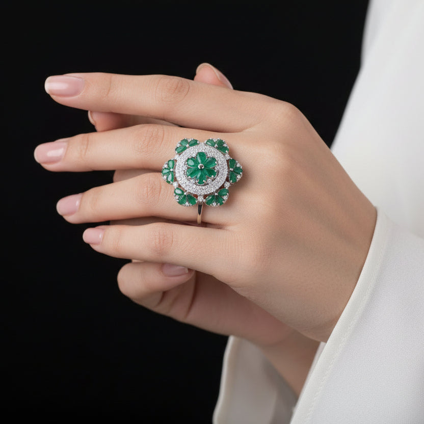 Jewelry ring with green gemstones and silver accents on a dark background, featuring the brand 'SAHELI'.
