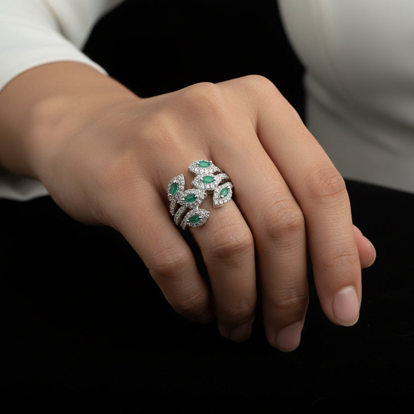 Silver ring with green gemstones on a gray background with 'SAHELI' branding.